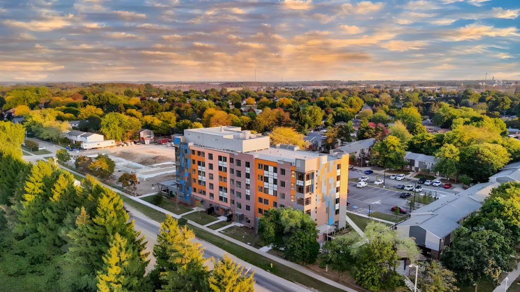 Completed multi-storey building beside an active construction area at sunset