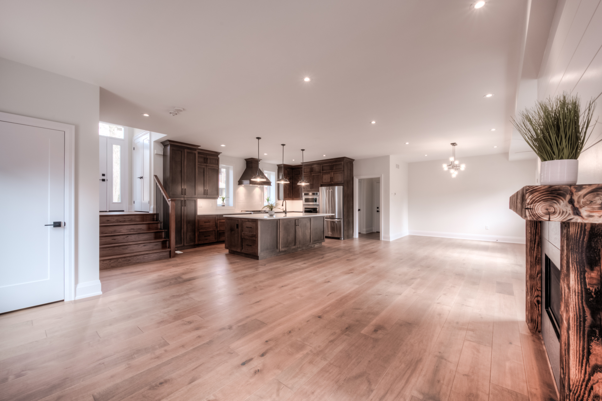Open-concept kitchen and living room with dark wood cabinetry, white counters, and hardwood floors