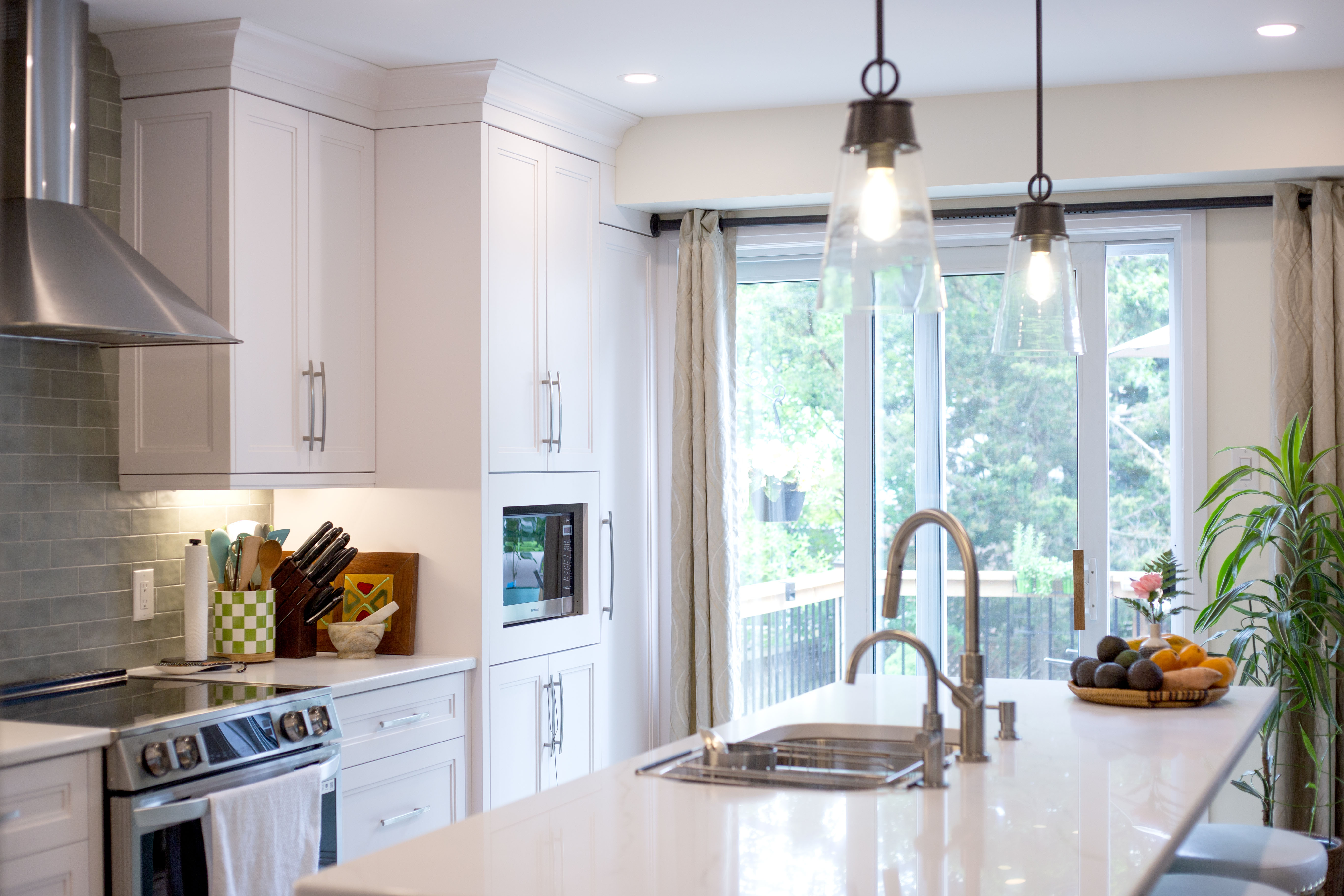 Custom kitchen with sage green island, subway tile backsplash, and pendant lighting